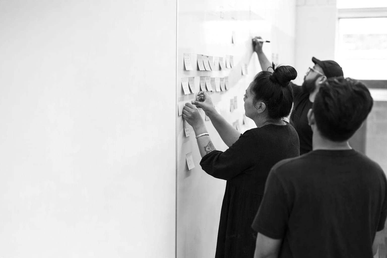 A small team at a whiteboard session, mapping stages of a delivery process