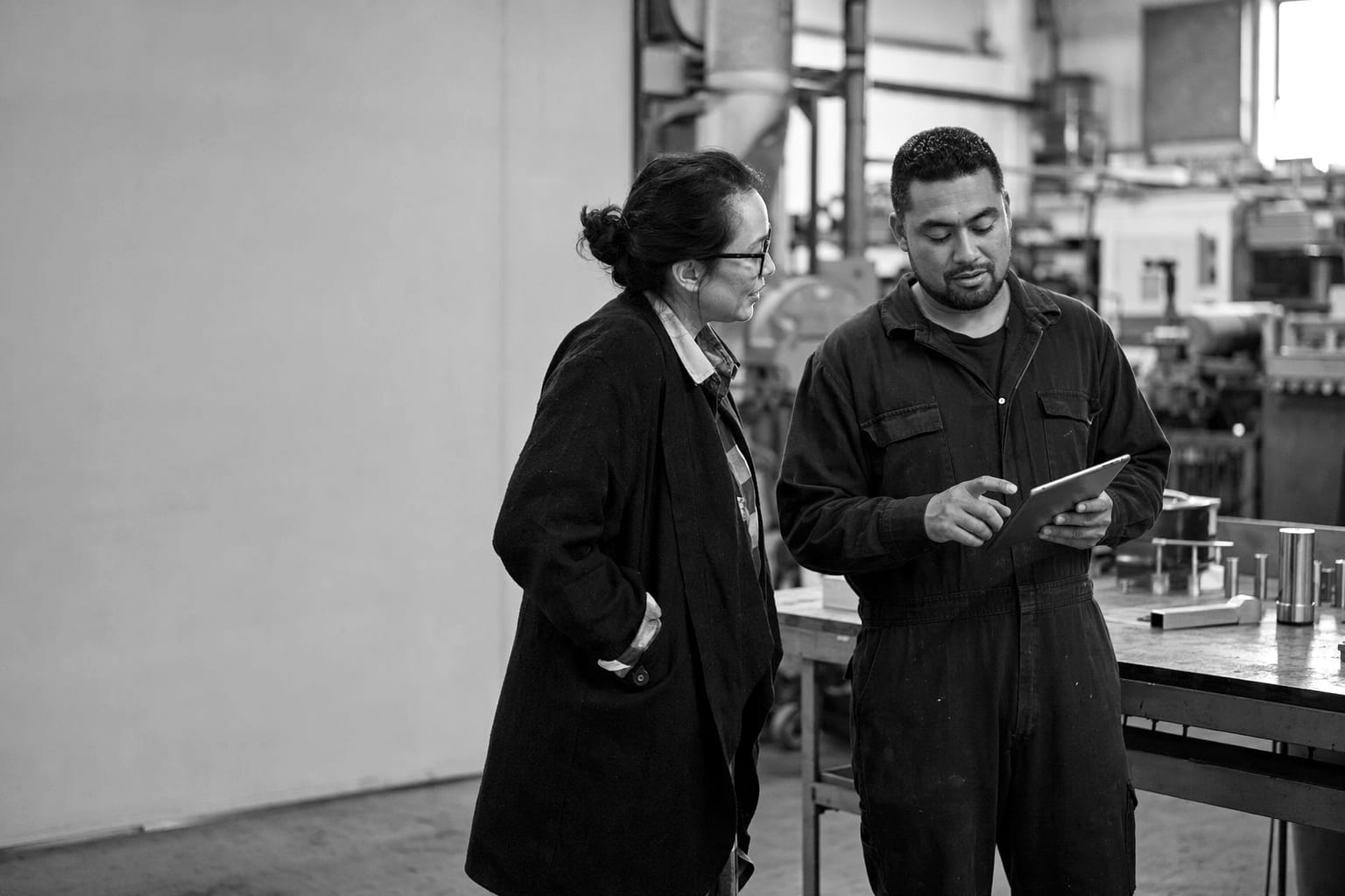 An advisor and a small business owner reviewing printed process maps together in a workshop